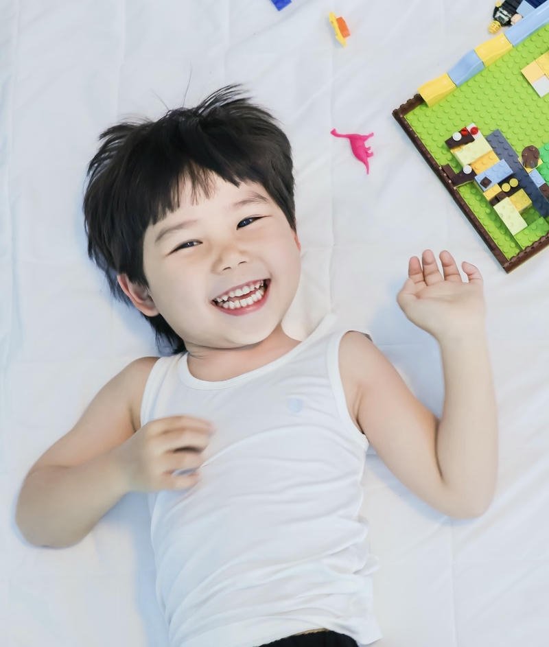 Bé trai đáng yêu đang nằm chơi đồ chơi trong phòng