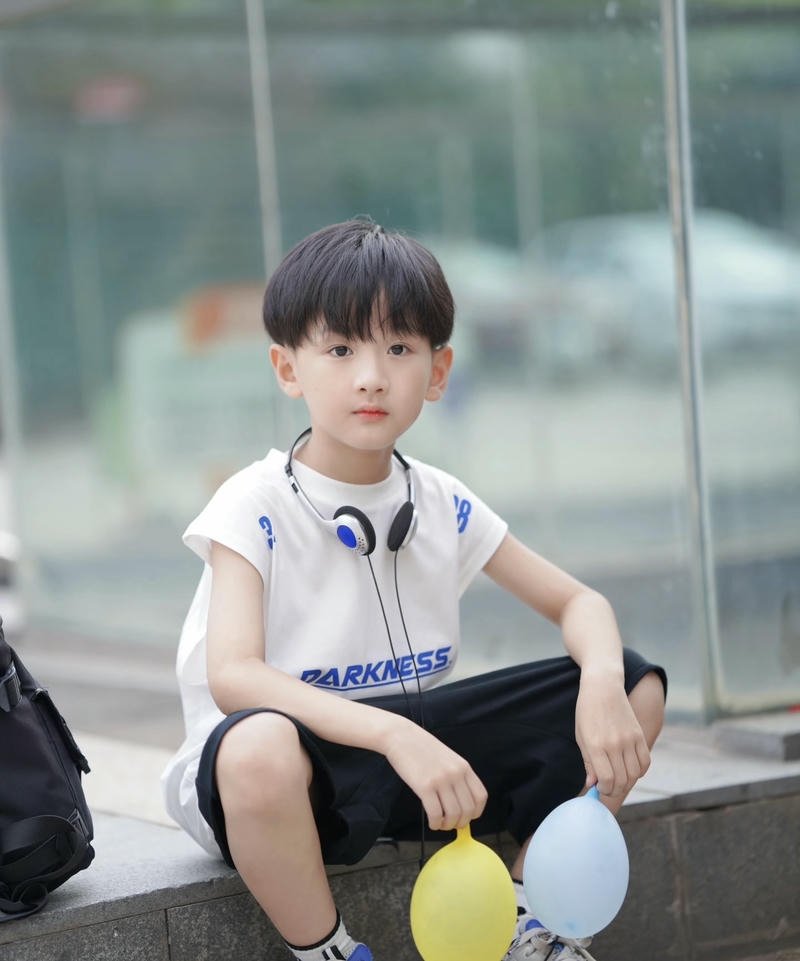 Bé trai ngồi trên lề đường cực dễ thương