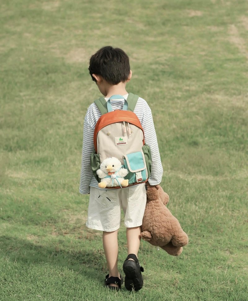 Cậu bé quay lưng giữa bãi cỏ rộng trong ánh nắng