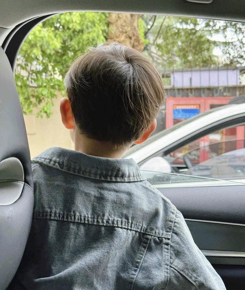 Cậu bé quay lưng ngồi trong ô tô nhìn ra đường phố