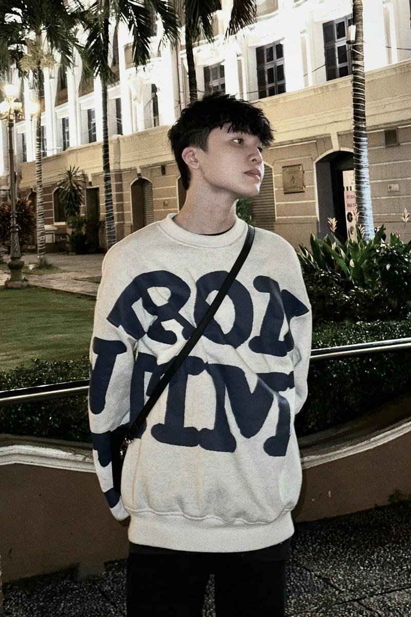 Chàng trai Việt Nam đứng cạnh tường đơn giản