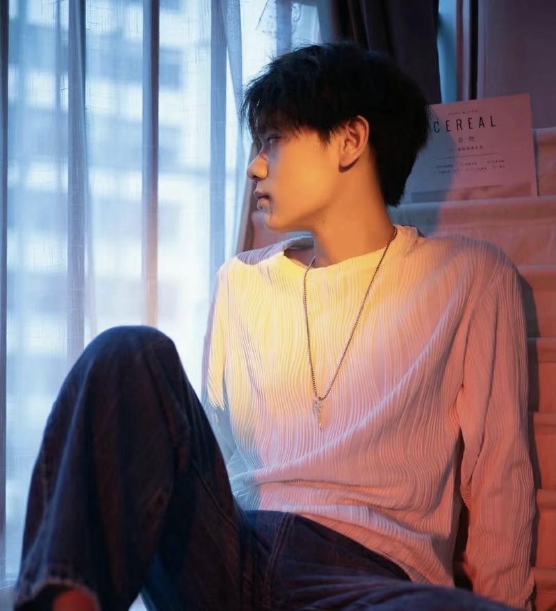 Chàng trai ngồi bên cửa sổ mang hình ảnh tâm trạng con trai