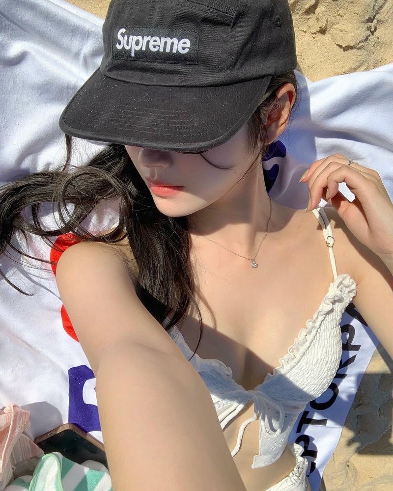 Cô gái trẻ mặc váy ngắn đi dạo bãi biển da trắng