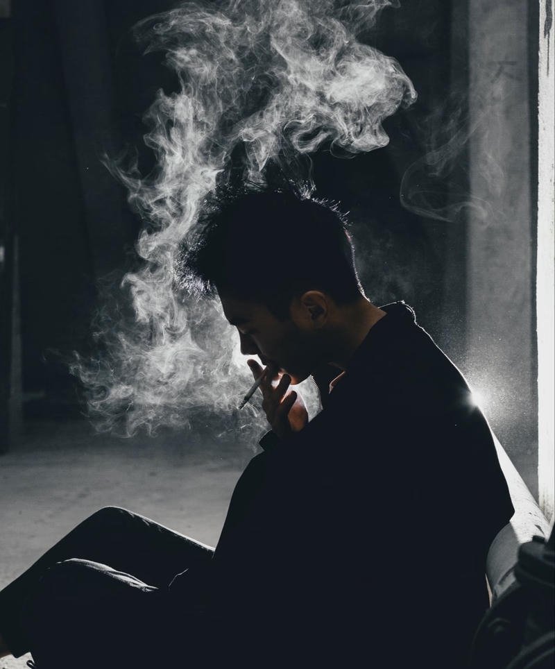 Người con trai trầm ngâm ngồi hút thuốc đầy tâm trạng